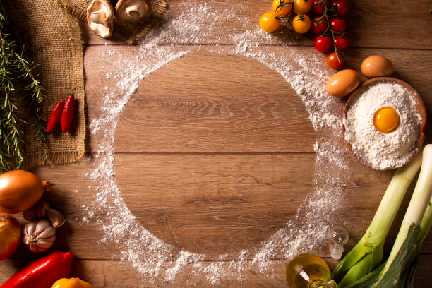 istock Various vegetables at wooden rustic background with copyspace on round pizza desk. Set of fresh vegetables. Egg, tomatoes, pepper, lettuce, onion, garlic, onion. Pizza ingredients. 1286565571