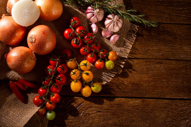 istock Vegetables on a wooden table top view. Tomato, garlic and onion. 1286567102