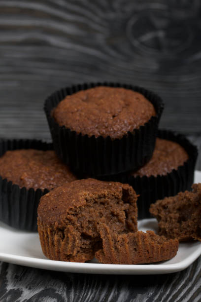 istock Oatmeal chocolate muffins. Drawn up on a silver platter. One is broken to show a cut. On black pine boards. 1286567430