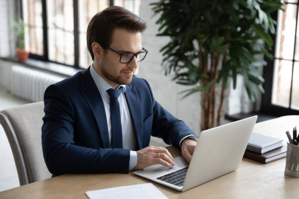 istock Smiling young businessman working on project online. 1286567819
