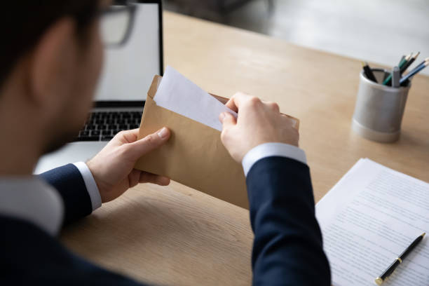 istock Focused young male ceo executive manager opening envelope with correspondence. 1286567857