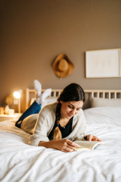 istock Woman reading a book on a bed 1286568931