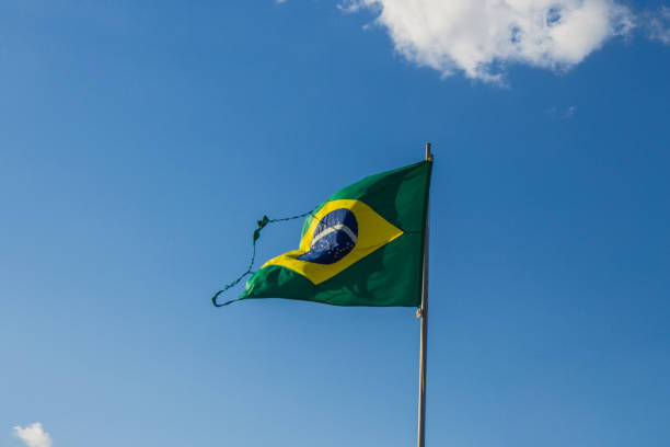 istock Torn brazilian flag and blue sky 1286569062