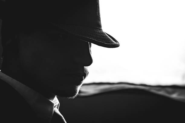 Retro man in hat wears suit and tie, black and white. Noir style.