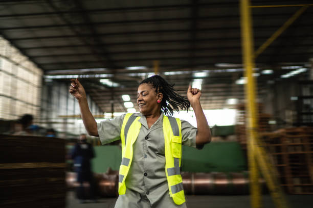 glückliche reife frau tanzen in einer branche - industriearbeiter stock-fotos und bilder