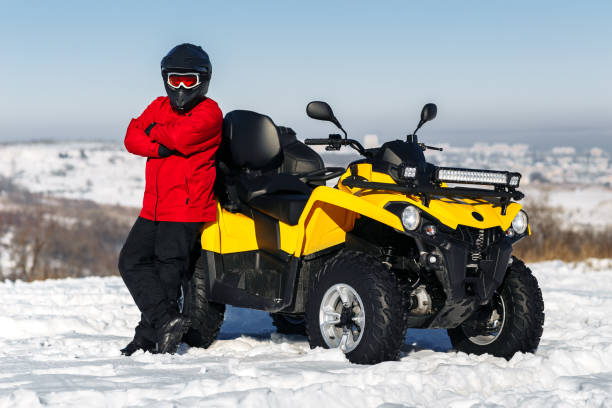 młody kierowca mężczyzny pozujący na quadzie atv stoi w ciężkim śniegu z głębokim torem koła. moto sporty zimowe. - off road vehicle quadbike quad racing motocross zdjęcia i obrazy z banku zdjęć