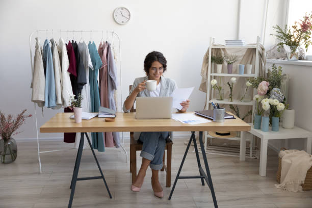 istock Smiling woman designer consider paperwork in modern office 1286575372