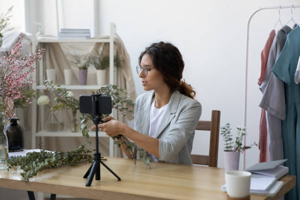 istock Female florist shoot floral decorations tutorial on cellphone 1286575901