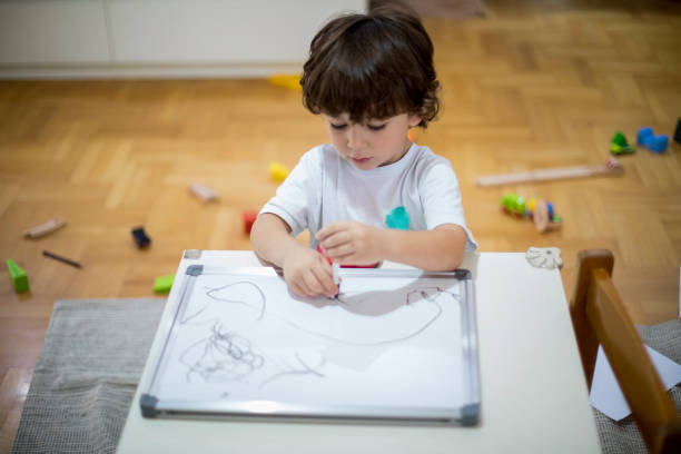 istock Beautiful toddler boy drawing on the white board. 1286576528