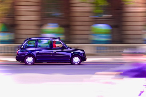 Blurred London taxi cab in motion, slightly surreal with purple tint