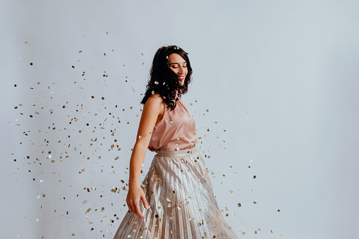 Beautiful Smiling Black-Haired Woman Dancing under Confetti in a Long Elegant Skirt