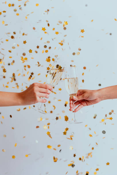 istock Wedding Day: Hands of Two Anonymous Women Clinking Glasses under Confetti at a Wedding Reception 1286580764