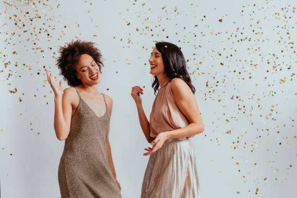 istock Party Time: Two Cheerful Young Women Dancing in Confetti Rain (White Background) 1286580776