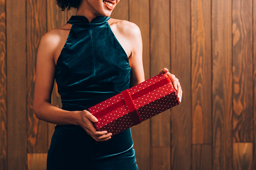 Hands of an unrecognizable smiling young woman holding a red gift