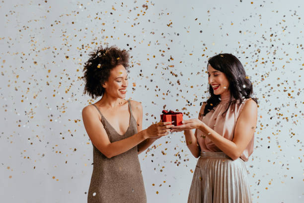 istock Merry Christmas: Two Smiling Young Women Exchanging Christmas Presents at a Party 1286580796