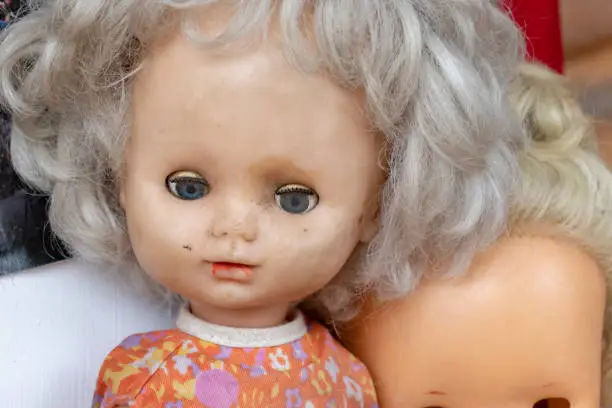 Photo of An old worn doll with dirty face close up, spooky view