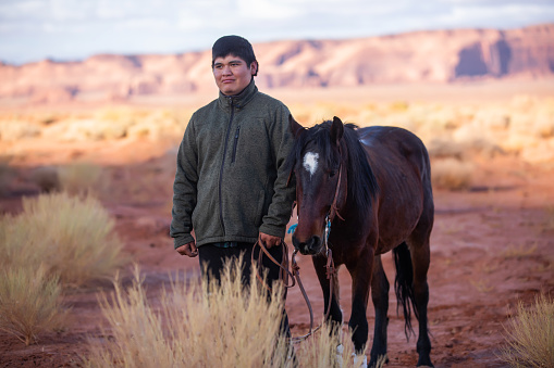 Navajo teen posing by his trusted horse in the Arizona desert
