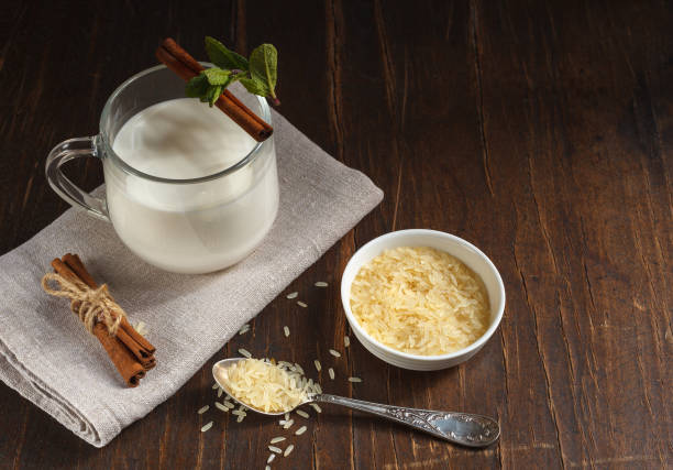 Rice vegetable milk in a glass cup with cinnamon and mint , a plate with white rice, top view with space stock photo