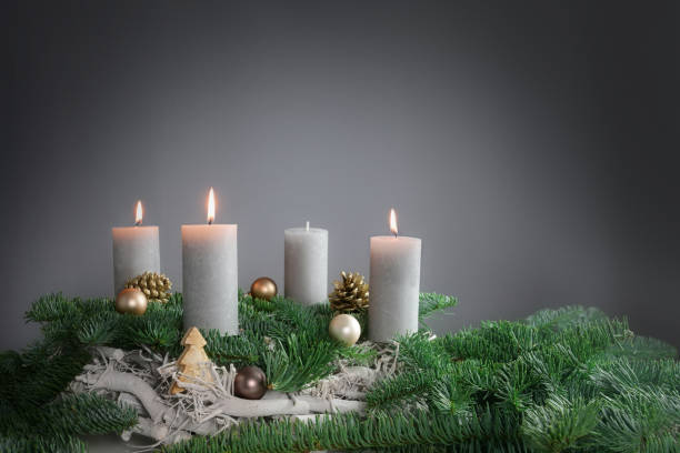 tre candele su quattro stanno bruciando per il terzo avvento su rami di abete con decorazione natalizia su sfondo grigio, spazio di copia - advent wreath foto e immagini stock
