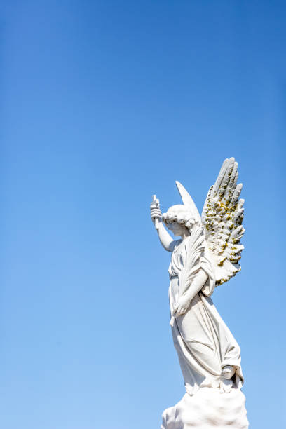 istock Angel, old statue of angle with cross, blue sky background with copy space 1286585503
