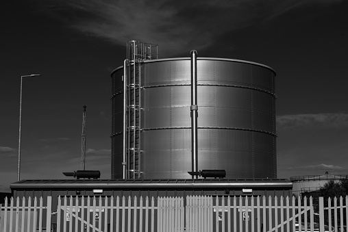 Oil storage tank and surrounding metal fence, photographed against the sky.  Belfast, Northern Ireland.