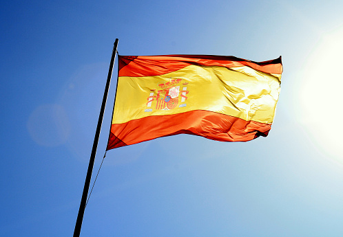 Backlit photograph of a waving Spanish flag.