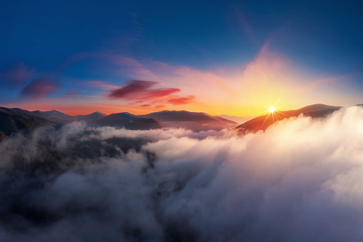 Dramatic sunset high in the mountains above the clouds from aerial view.