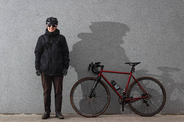 istock Smiling cyclist stands near gray concrete wall with bicycle. 1286586779