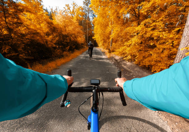 vista in prima persona di un ciclista che guida con un amico nella foresta autunnale. - racing bicycle bicycle cycling yellow foto e immagini stock