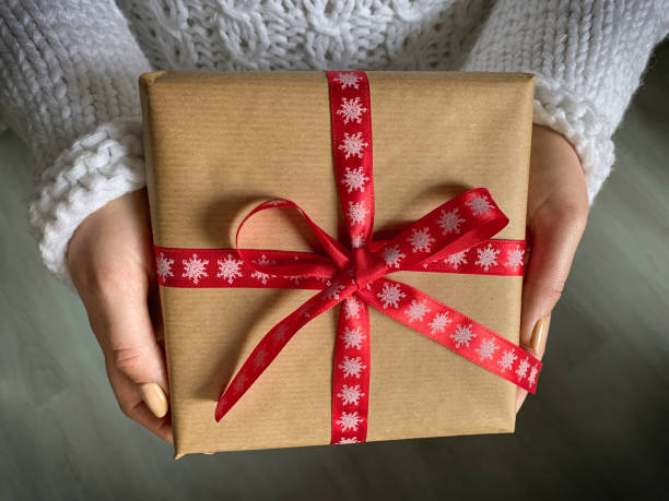 istock Close up hands holding gift box with bright red bow, christmas and new year concept. 1286587619