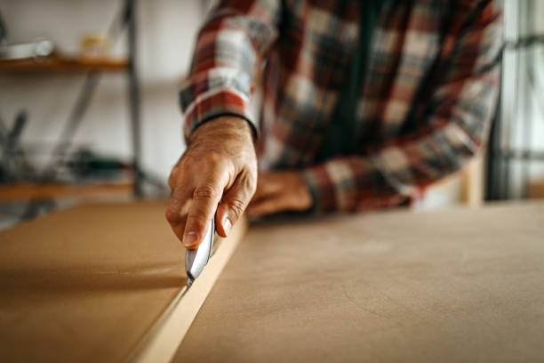istock Man opening cardboard package with scalpel at home 1286589853