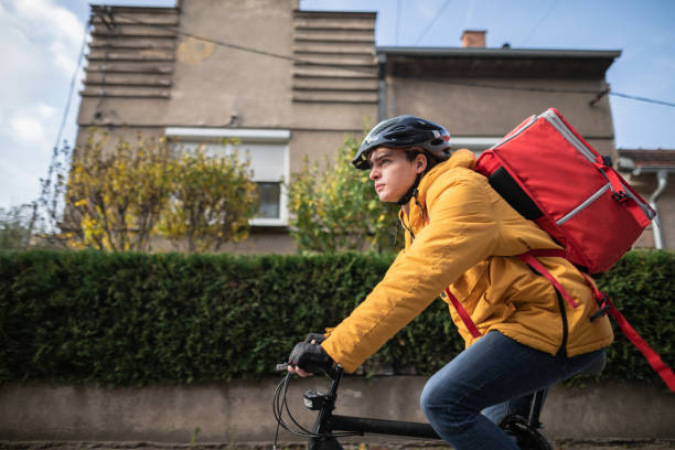 Delivery person cycling through city on his way to next customer stock photo