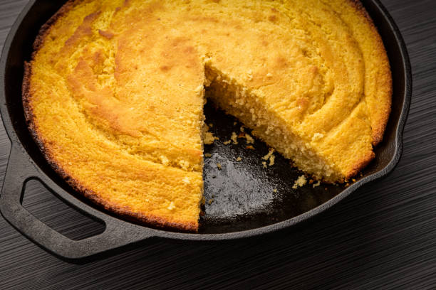 Corn bread baked in cast iron Fresh corn bread right out of the oven baked in a cast iron skillet with a slice removed skillet stock pictures, royalty-free photos & images