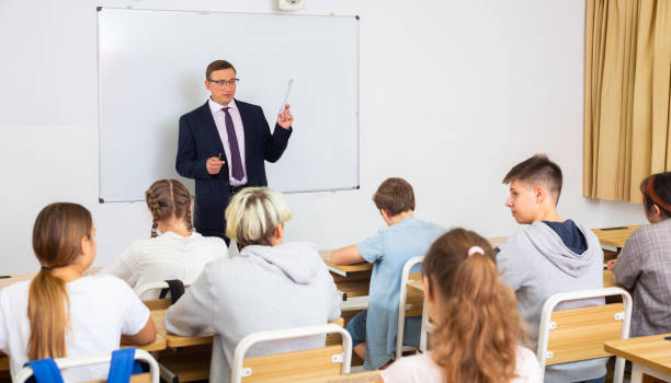 istock Man teacher with notebook is giving interesting lecture for students in classroom 1286594731