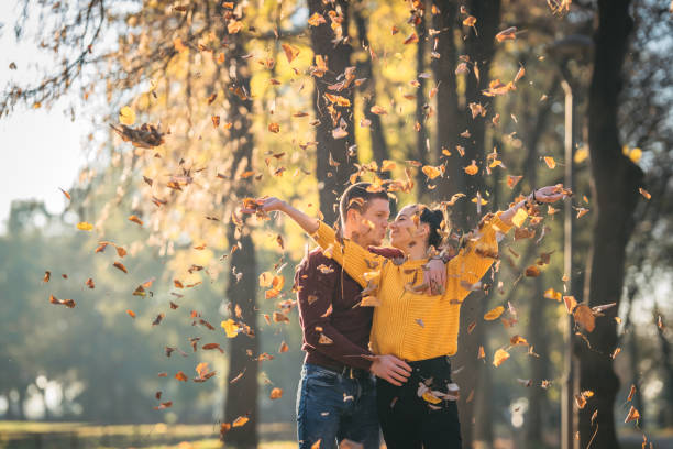 istock Cheerful couple playing with leaves in park during autumn 1286600191