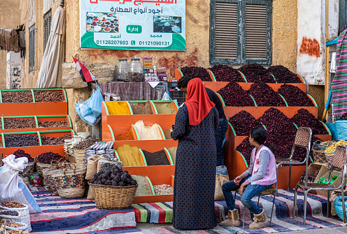 A traditional Egyptian woman shopping for spices at an Aswan souk.
