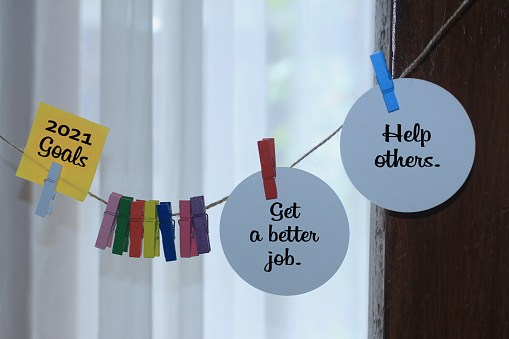 2021 New Year resolutions concept with notes hanging on the rope. 2021 goals - Get a better job. Help others.