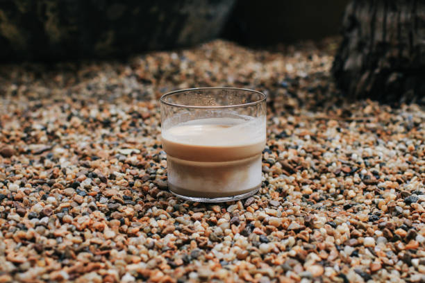 Dirty coffee latte on abstract colorful mini granite crushed stones ground texture background. Light and shadow in morning.