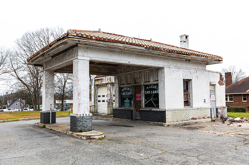 Kings Mtn, NC, USA-4 March 2020: An abandoned old-style gas station building, last called Parker's Car Care, on a main street, with a for sale sign in window.