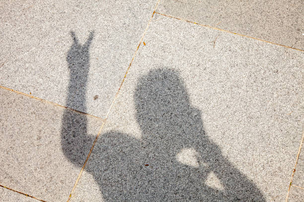 istock Shadow Of Person Making The Peace Sign On A Concrete Floor 1286613108