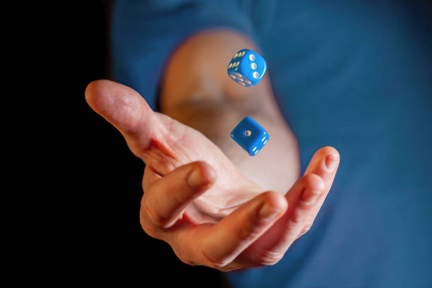 Caucasian male hand throwing blue dice cubes in the air - closeup with shallow focus stock photo