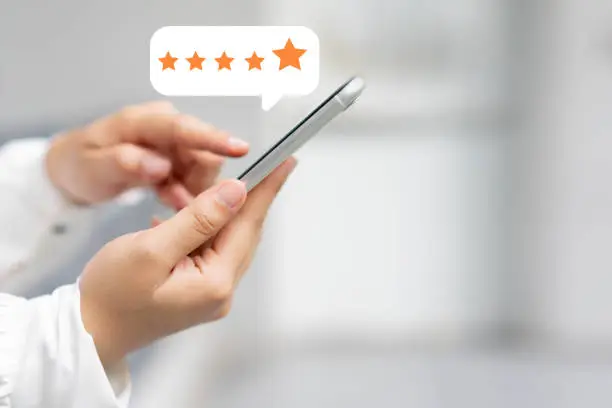 Photo of close up on customer woman hand pressing on smartphone screen with  five star rating feedback icon and press level excellent rank for giving best score point to review the service , technology business concept