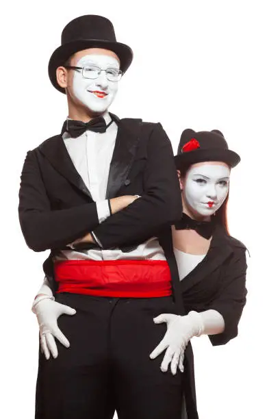 Portrait of two mime artists performing, isolated on white background. Mime hid behind his friend, putting hands on his hips.
