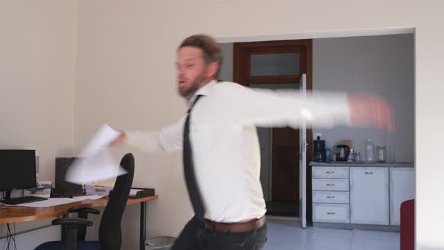 Middle adult man with papers trips and falls in the office