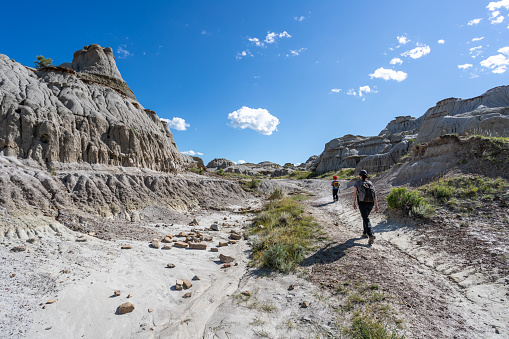 Mother and Son Hiking in Badlands of Dinosaur Provincial Park in Alberta, Canada. It is a beautiful summer sunny day. They are bonding while hiking in the park’s footpath.
