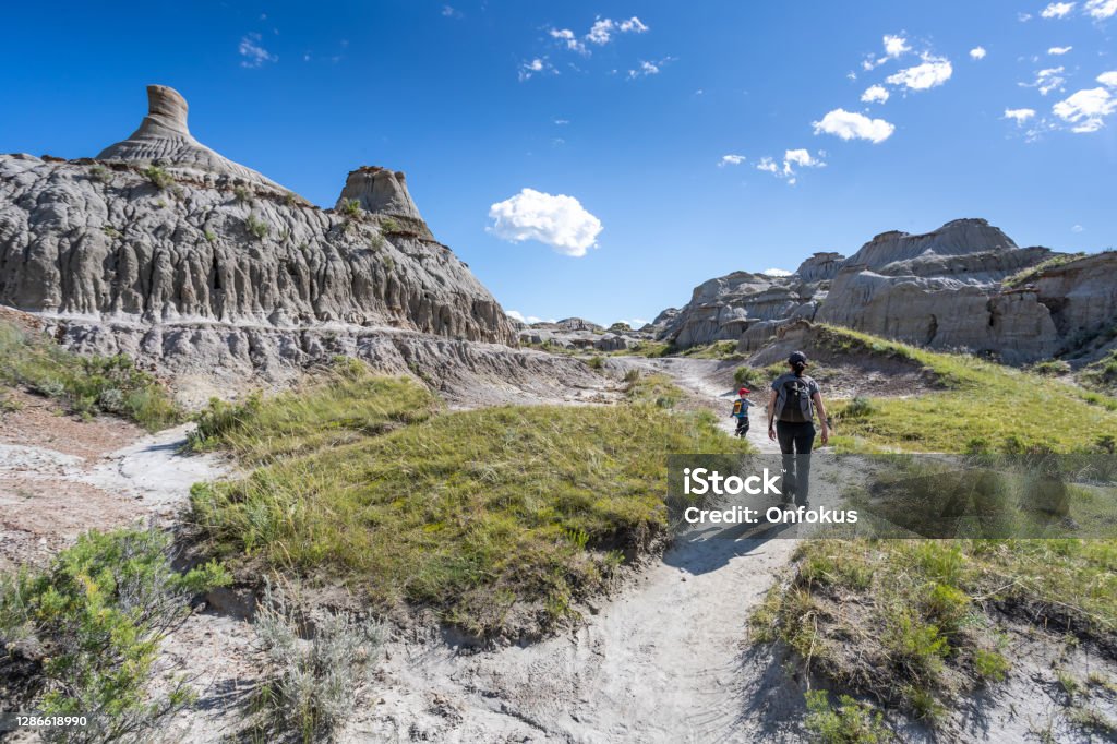 Mother and Son Hiking in Badlands of Dinosaur Provincial Park in Alberta, Canada Mother and Son Hiking in Badlands of Dinosaur Provincial Park in Alberta, Canada. It is a beautiful summer sunny day. They are bonding while hiking in the park’s footpath. Drumheller Valley Stock Photo