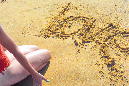 Love word is written by hand on the beach sand .