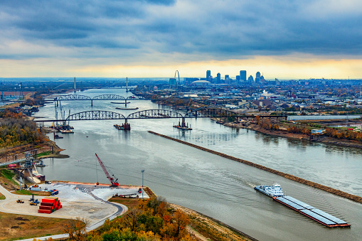 A barge and tugboat moving away from the downtown area of St. Louis, Missour along the Mississippi River.