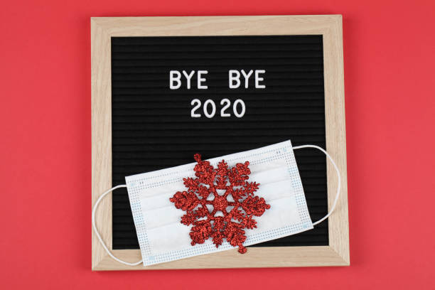 istock black letter board with text BYE BYE 2020 with mask and red snowflake on red background. Top view. flat lay New Year Christmas minimal background 1286626099