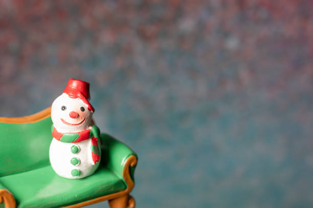 model with a snowman sitting on a green sofa against a bokeh background with copy space